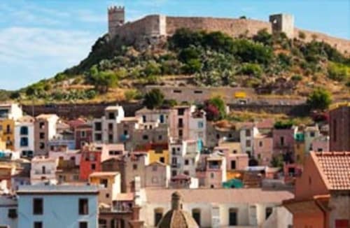 Casas coloridas en Torre Grande con ruinas del castillo en la cima de la colina, Oristano Italia