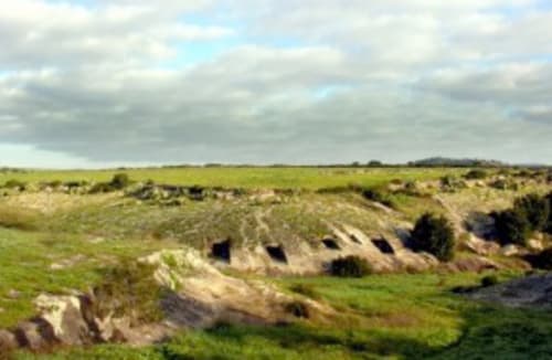 Paisaje de campiña ondulante cerca de Torre Grande Oristano con campos verdes y ruinas antiguas dominando el horizonte