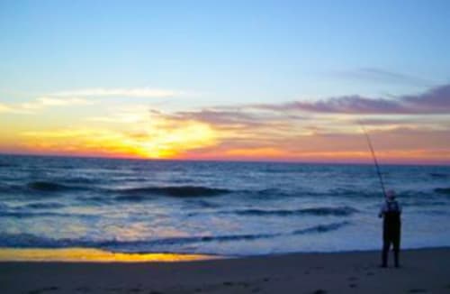 Pescatore al tramonto sulla spiaggia di Torre Grande, Oristano, Italia