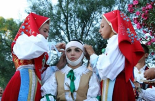 Niños con trajes sardos rojos tradicionales en la celebración de Torre Grande Oristano