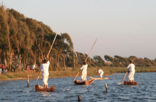 Veleros tradicionales en el agua cerca de Torre Grande Oristano con vegetación de caña a lo largo de la orilla