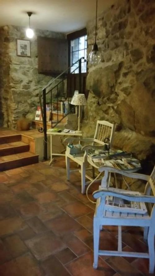 Escalera rústica de piedra en La Posada Del Tietar con sillas azules, peldaños de madera y luz natural en Santa María del Tiétar