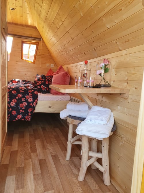 Cozy wooden cottage bedroom at Les Refuges Du Chalet with bed, floral bedding, shelf with flowers, and folded towels in