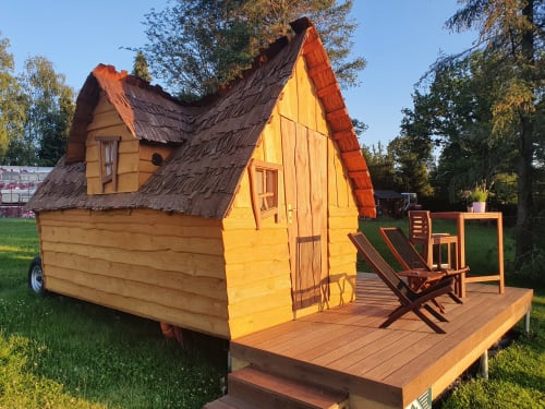 Whimsical yellow wooden cottage with steep roof at Les Refuges Du Chalet, Jalhay, featuring deck and garden views