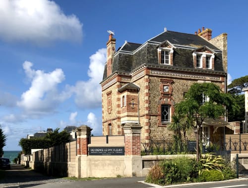 Résidence Le Roc Fleuri, une élégante demeure en pierre et brique à Saint-Malo, avec toit mansardé et murs couverts de lierre.
