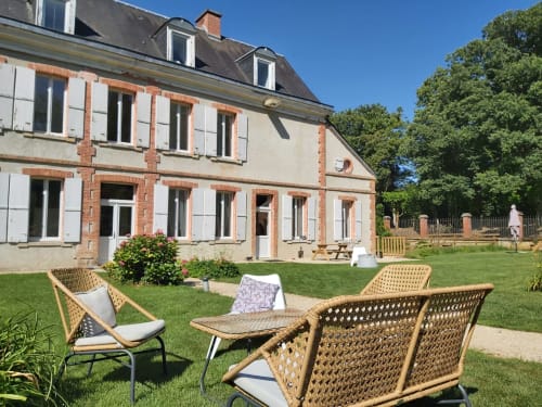Coin détente en rotin sur pelouse impeccable face à la maison en brique du Château de la Malmaison, Aÿ-Champagne