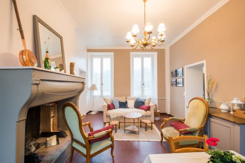 Salon élégant du cottage L'âtre au Château de la Malmaison en Champagne avec cheminée, lustre et vue sur le jardin