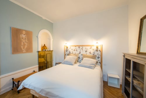 Chambre élégamment aménagée au Château de la Malmaison à Aÿ, Champagne, avec lit en bois, tête de lit floral et vue sur le jardin