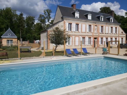 Piscine du Château de la Malmaison, gîte de charme en Champagne, avec chaises longues et manor en pierre