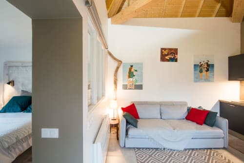 Espace de vie moderne du Château De La Malmaison en Champagne avec canapé gris, coussins rouges et œuvres d'art murales