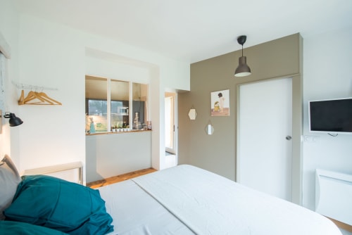 Chambre moderne avec literie bleu-vert, kitchenette et TV au Château De La Malmaison à Aÿ-Champagne