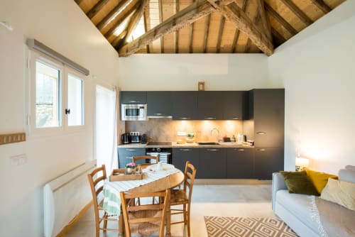 Cuisine et salle à manger contemporaines au charme rustique avec poutres en bois apparentes, mobilier noir et vue sur le jardin du Château