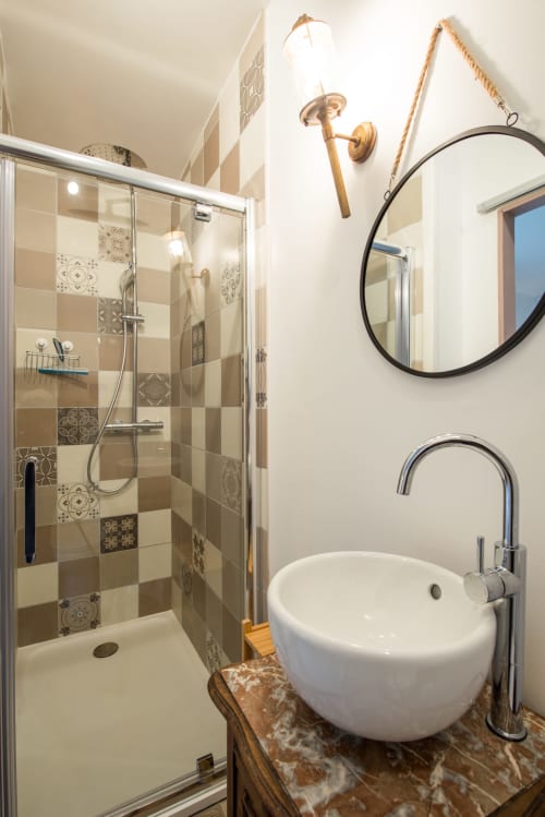 Salle de bain moderne du gîte Château De La Malmaison avec lavabo rond, pomme de douche pluie et mur d'accent en carrelage décoratif