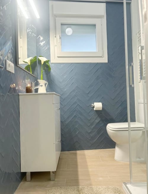 Baño moderno del apartamento Holibai en Baiona con paredes de azulejos en espiga, tocador blanco, inodoro y cabina de ducha