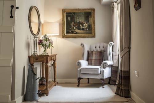 Elegant sitting area at Three Little Pigs Luxury Cottage in Blandford Forum with white wingback chair, wooden console table,