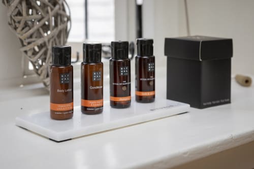 Luxury toiletries displayed on white tray at Three Little Pigs cottage, featuring organic body lotion, conditioner and
