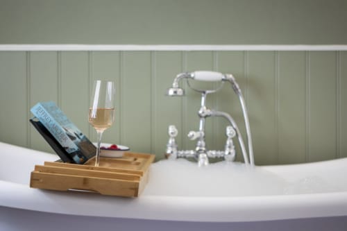 Luxury bathroom at Three Little Pigs cottage featuring a soaking tub with champagne and vintage faucet