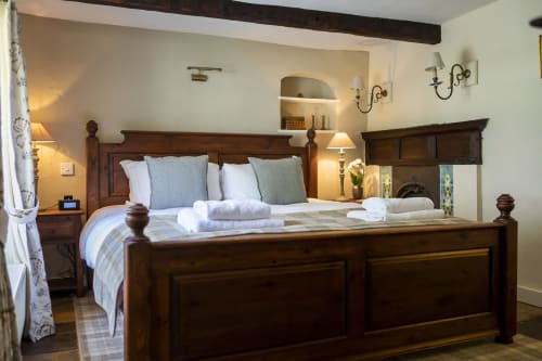 Luxury cottage bedroom at Three Little Pigs, Blandford Forum, with wooden bed, blue pillows, white towels, and warm lighting.