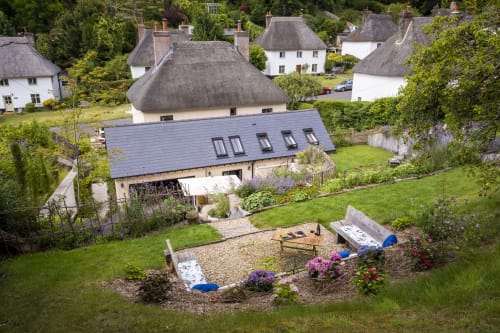 Three Little Pigs luxury cottage in Blandford Forum with thatched roof, garden, and outdoor seating area surrounded by lush