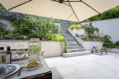 Three Little Pigs luxury cottage patio in Blandford Forum with dining area, umbrella, tiered gardens, and stone steps.