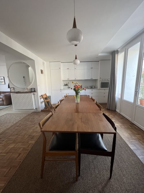 Salle à manger cottage moderne avec table en bois, chaises et centre de table fleuri au Gite Moderne à Dunkerque