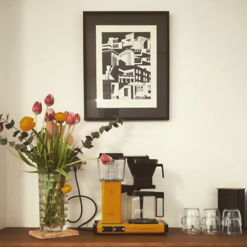 Espace de travail du gîte moderne avec cafetière jaune, fleurs fraîches et art urbain encadré à Dunkerque