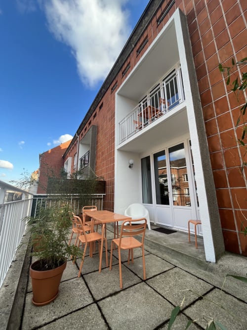 Patio moderne du Gîte Moderne à Dunkerque avec table à manger, chaises et balcon vue sur la ville