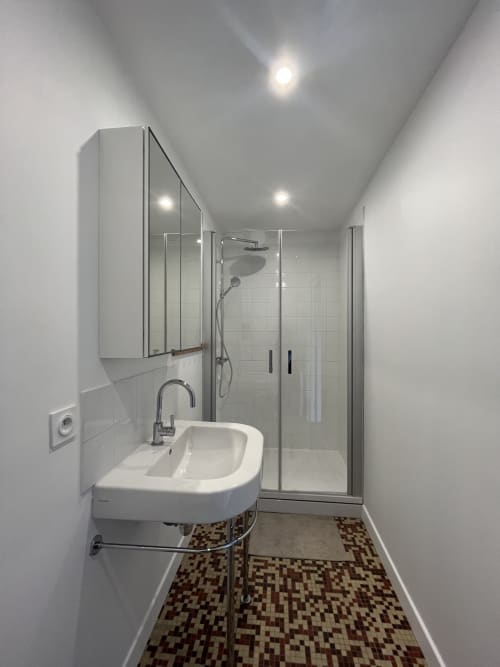 Salle de bains moderne du gîte Le Gite Moderne à Dunkerque avec lavabo blanc, douche à paroi vitrée et carrelage mosaïque