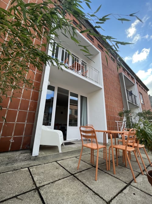 Terrasse cottage moderne au Gite Moderne, Dunkerque avec chaises en bois, dallage et accès balcon vue sur la ville