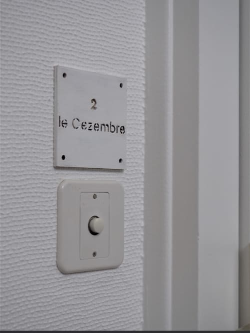 Mur blanc texturé avec plaque numérotée « 2 le Cézembre » et variateur à la Résidence Le Roc Fleuri, Saint