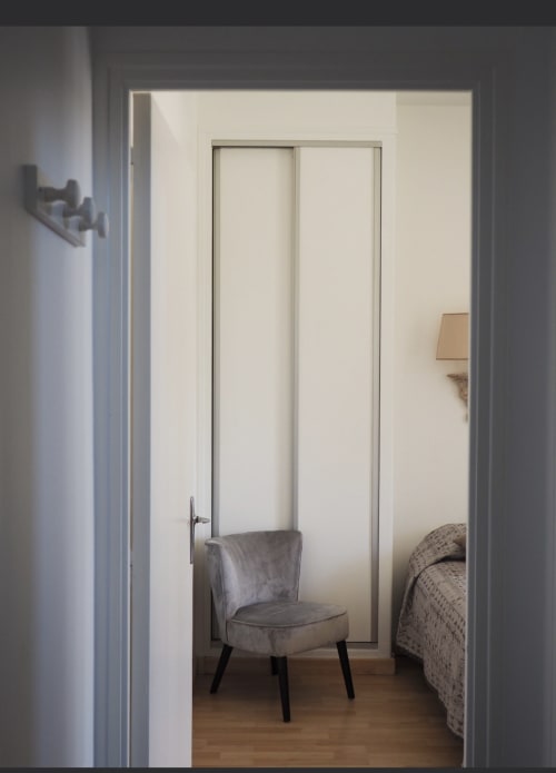 Chambre moderne à la Résidence Le Roc Fleuri à Saint Malo avec fauteuil gris, lit, portes de placard coulissantes et parquet