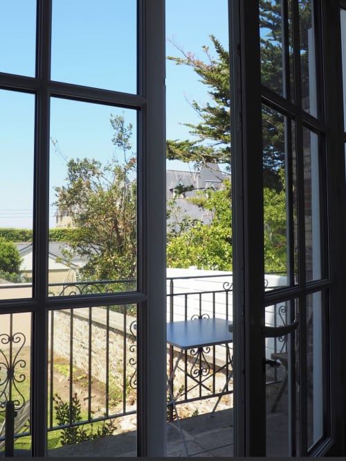 Portes aux cadres noirs ouvrant sur un balcon avec vue sur le jardin à la Résidence Le Roc Fleuri, Saint Malo