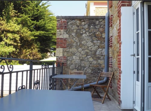 Espace de détente sur la terrasse de la Résidence Le Roc Fleuri à Saint-Malo avec chaises en bois et murs en pierre