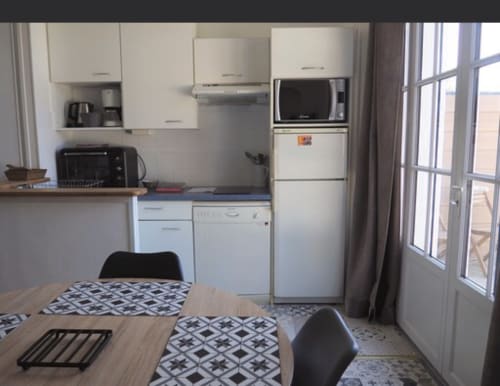 Cuisine compacte et salle à manger dans appartement de Saint-Malo avec réfrigérateur, cuisinière, micro-ondes et sol à motifs