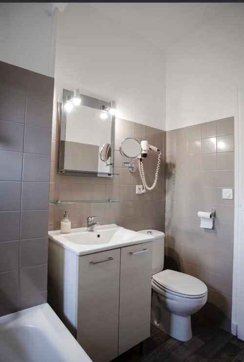 Salle de bain moderne à la Résidence Le Roc Fleuri à Saint-Malo avec lavabo, toilettes, miroir et murs carrelés