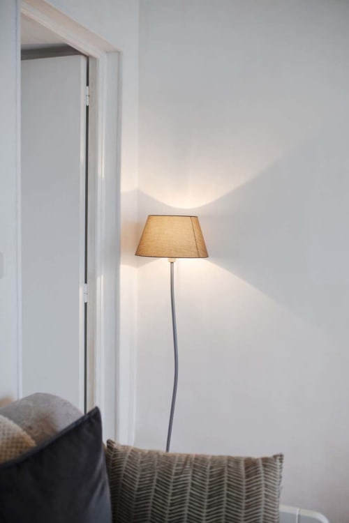 Coin minimaliste de la Résidence Le Roc Fleuri avec lampadaire lumineux et fauteuil texturé