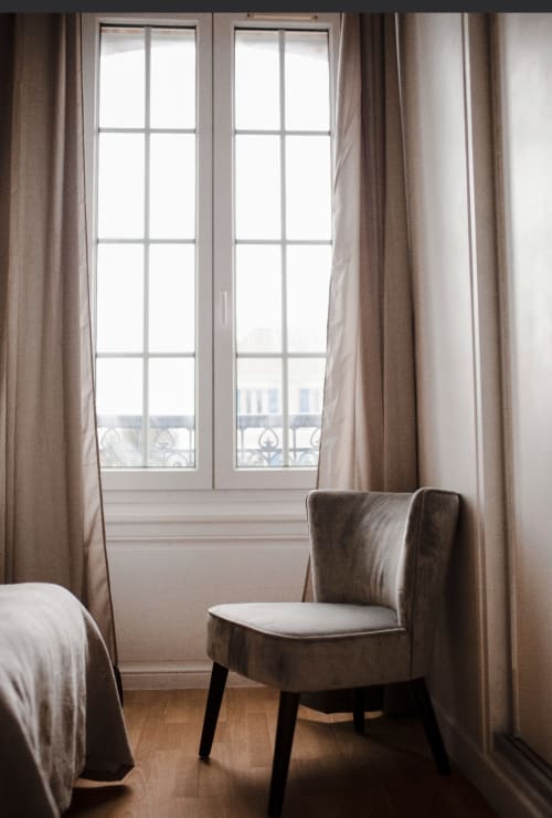 Chambre élégante à la Résidence Le Roc Fleuri, Saint Malo, avec vue sur mer, rideaux beige et coin détente confortable