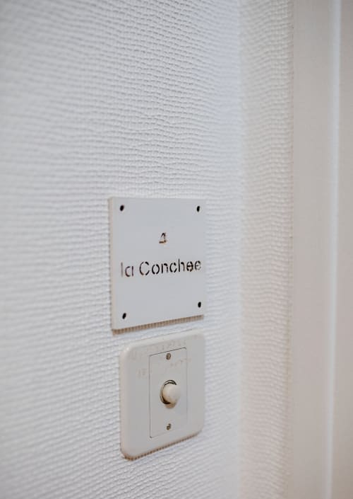 Interrupteur mural et plaque « La Conchae » dans un appartement de la Résidence Le Roc Fleuri, Saint Malo