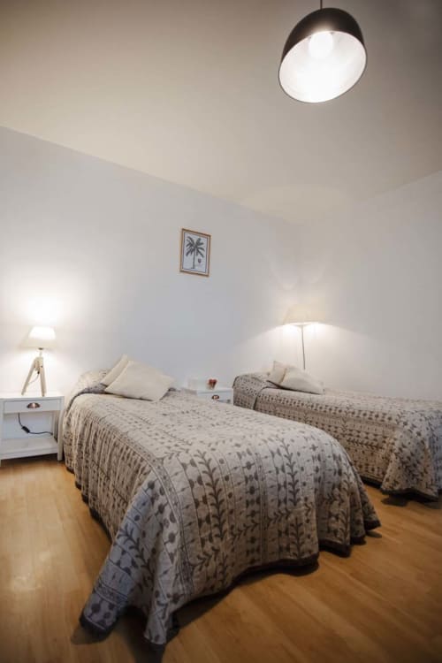 Chambre lumineuse avec deux lits à la Résidence Le Roc Fleuri à Saint-Malo, décorée de housses motifs et lampes de chevet