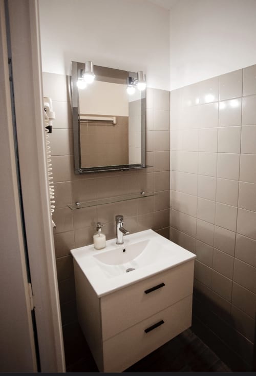 Salle de bain moderne avec vanité blanche, lavabo et miroir lumineux à la Résidence Le Roc Fleuri à Saint-Malo