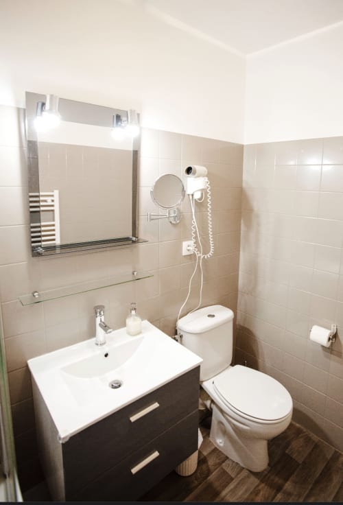 Salle de bains moderne à la Résidence Le Roc Fleuri, Saint Malo avec vasque, toilettes, miroir et sèche-cheveux mural
