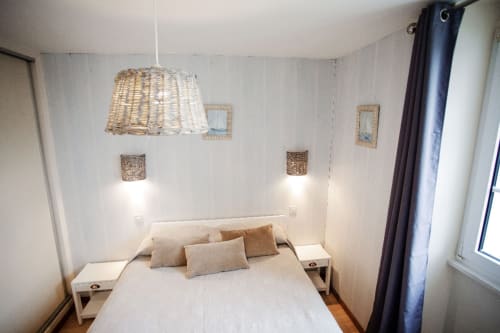 Chambre moderne à la Résidence Le Roc Fleuri à Saint-Malo avec lit blanc, luminaire suspendu tressé et décoration côtière