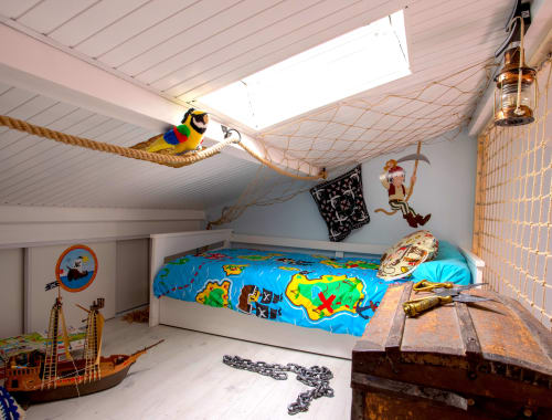 Chambre d'enfants sur le thème pirate au Pirate Benèze avec balançoire en corde, perroquet coloré et décoration voilier