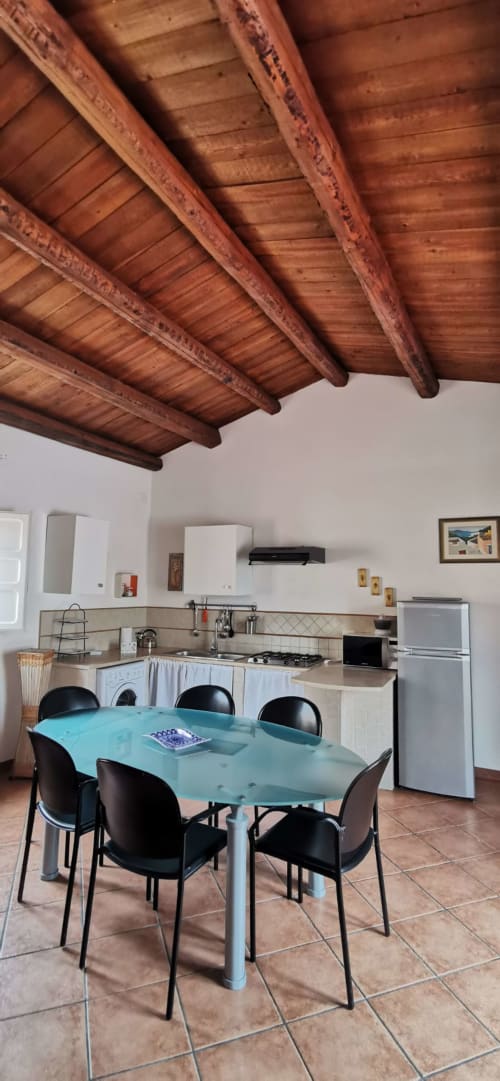 Modern kitchen and dining area in Casa Bellini Palermo apartment with exposed wooden beams and turquoise table