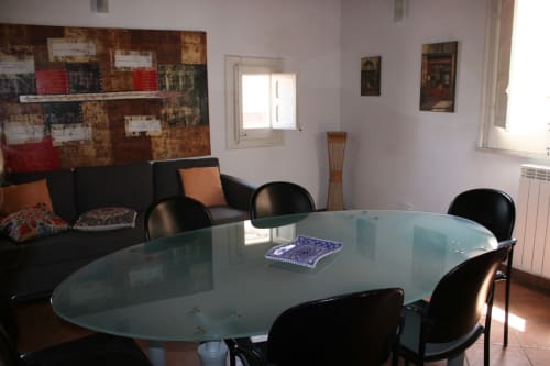 Modern dining room in Casa Bellini apartment, Palermo with glass table, black chairs, and living area with sofa