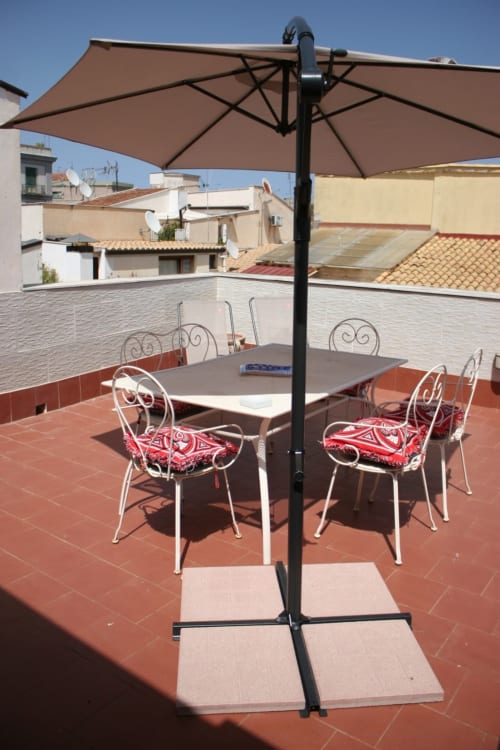 Private terrace at Casa Bellini with shaded dining table, chairs, and city view of Palermo