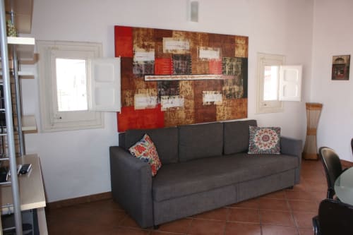 Modern living room in Casa Bellini Palermo apartment with dark sofa, abstract artwork, and terracotta flooring