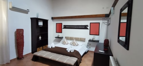 Modern bedroom at Casa Bellini in Palermo with dark furnishings, white bedding, red accents, and city view decor
