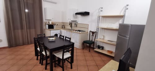 Primo Apartment dining and kitchen area at Casa Bellini in Palermo with black table, chairs, and stainless steel appliances