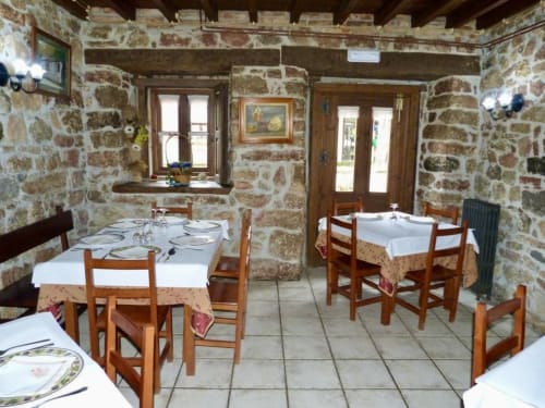 Comedor rústico de piedra en Hotel Rural Los Texos con mesas de madera, manteles blancos y paisaje típico del campo español